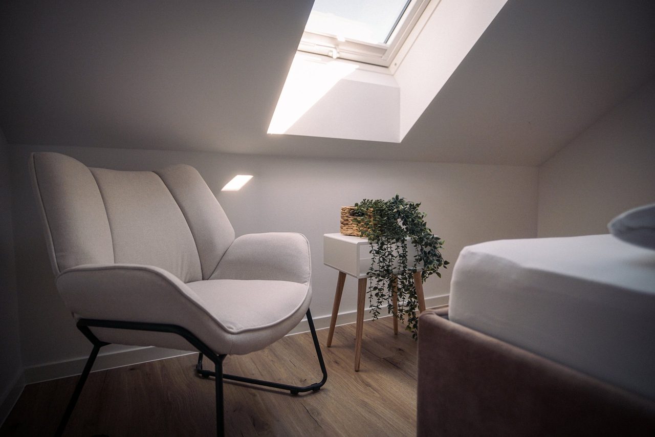 Sessel und Bett unter dem Dachfenster