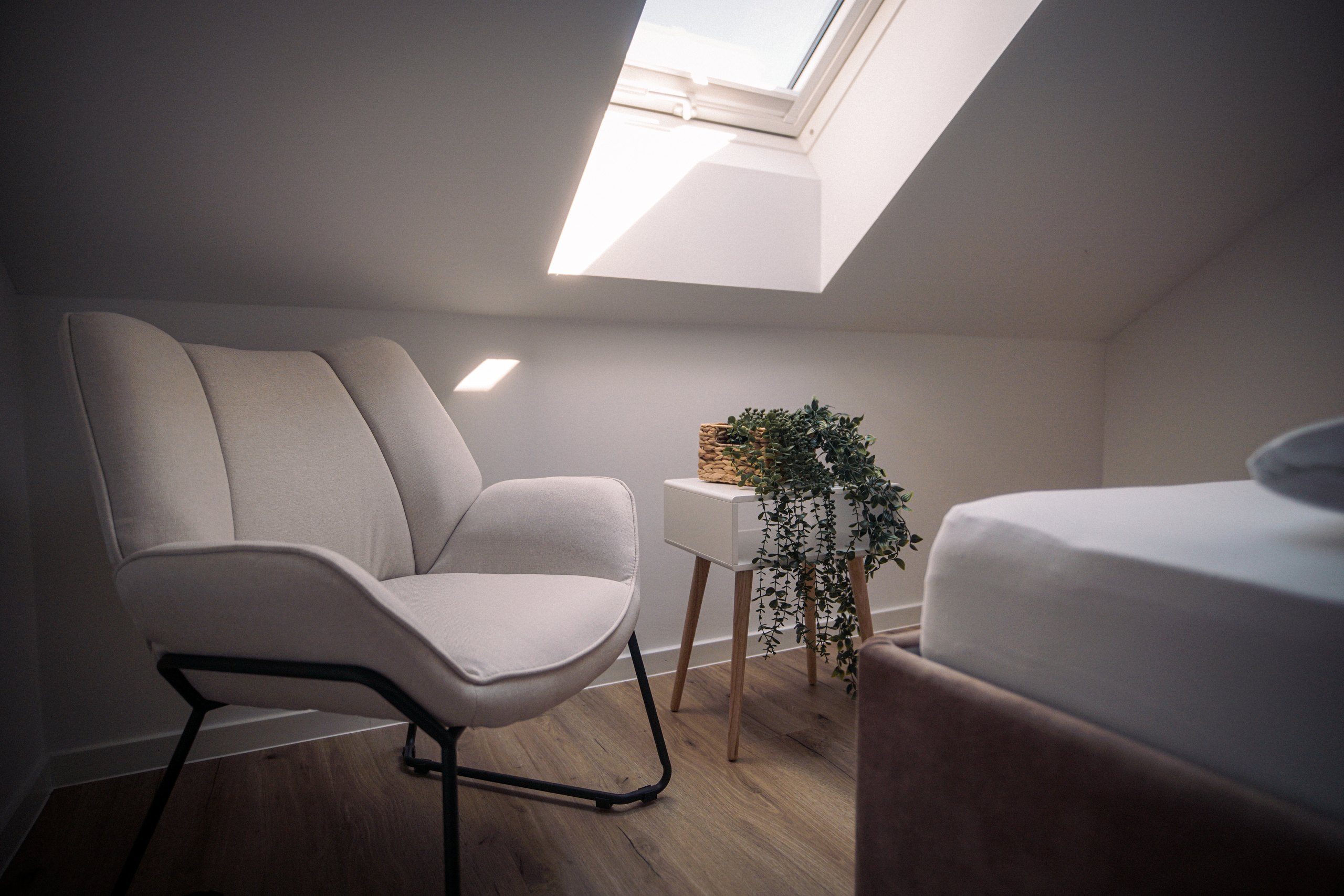 Sessel und Bett unter dem Dachfenster